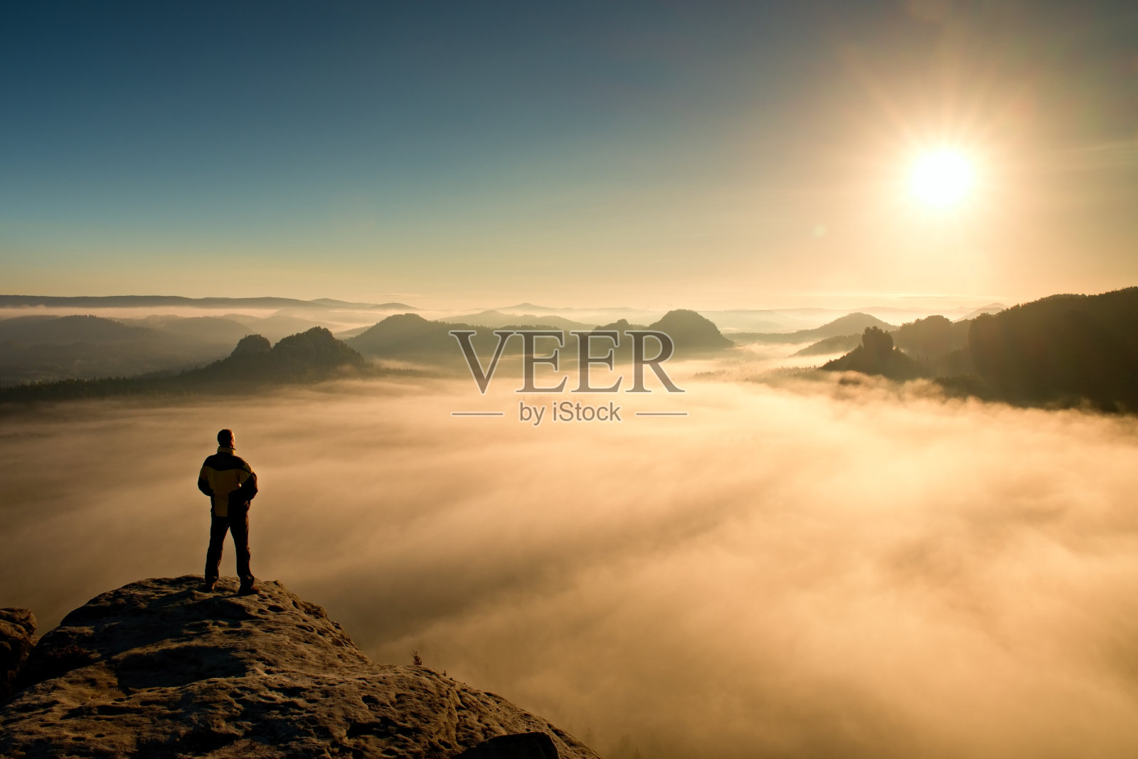 人站在山顶，望着太阳。美丽的奇迹照片摄影图片