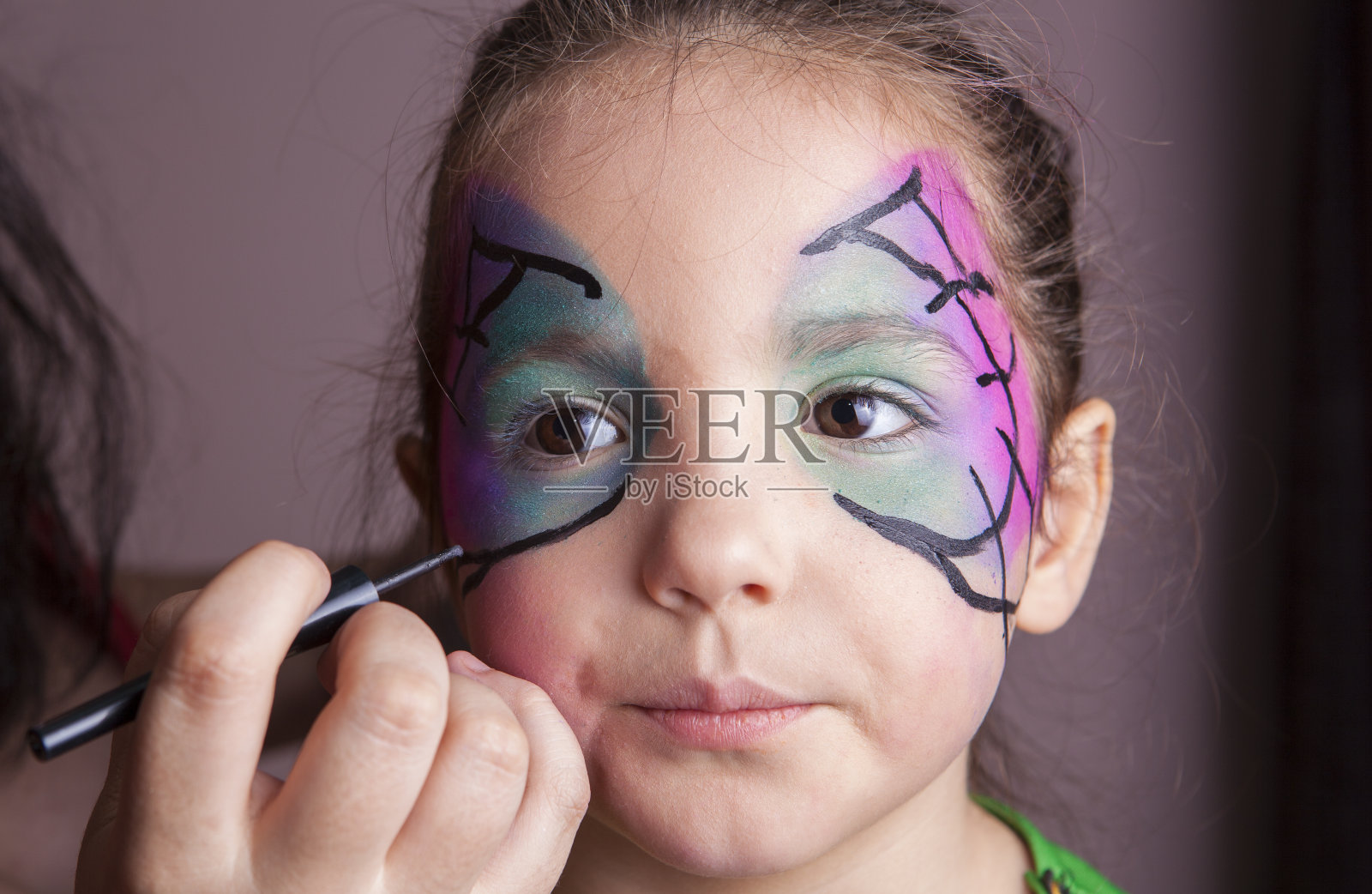 化妆艺术家在万圣节前夕与一个小女孩工作照片摄影图片