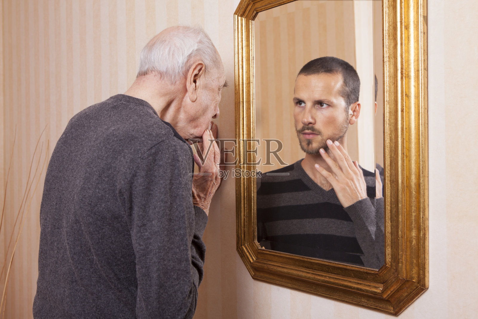 年长的人看着镜子里年轻的自己照片摄影图片