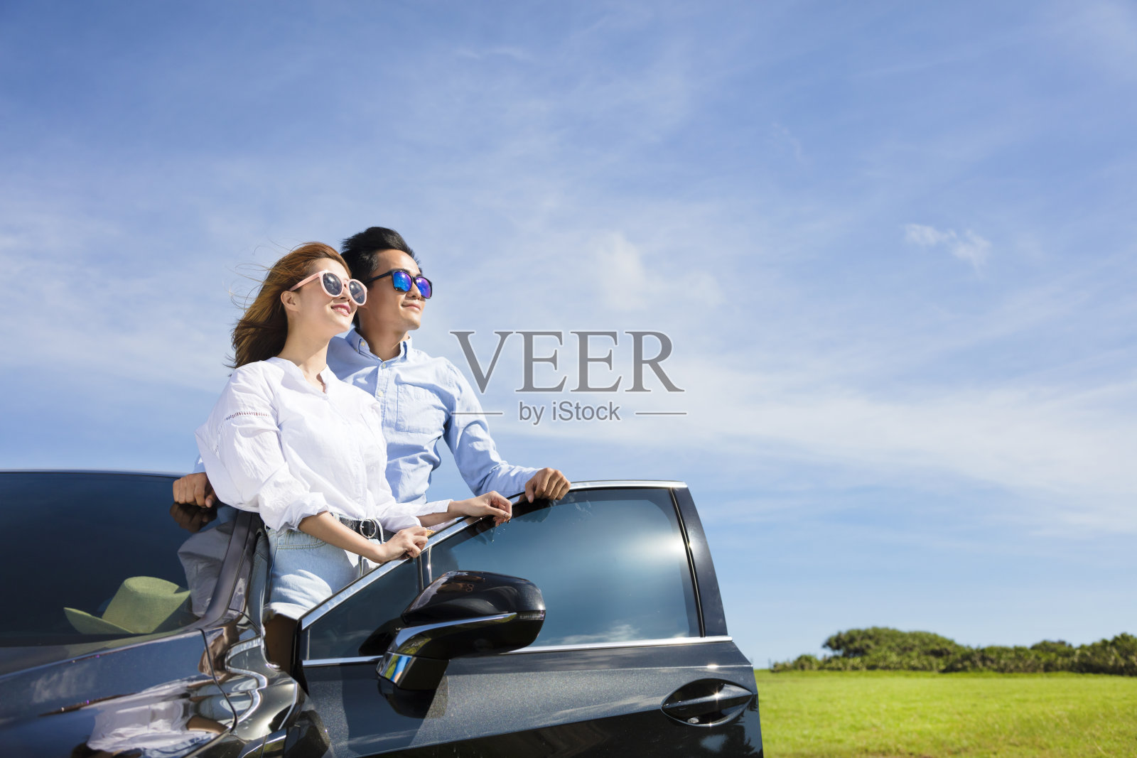 一对年轻夫妇站在车旁，享受暑假照片摄影图片
