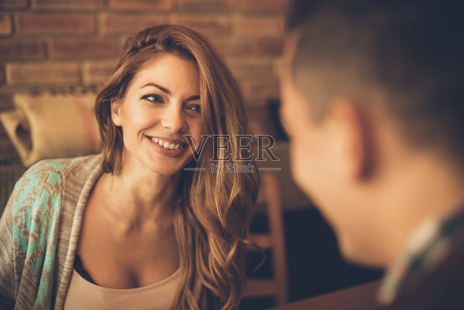 一个年轻的女人有一个大大的微笑，看着一个男人在一张桌子在咖啡馆照片摄影图片