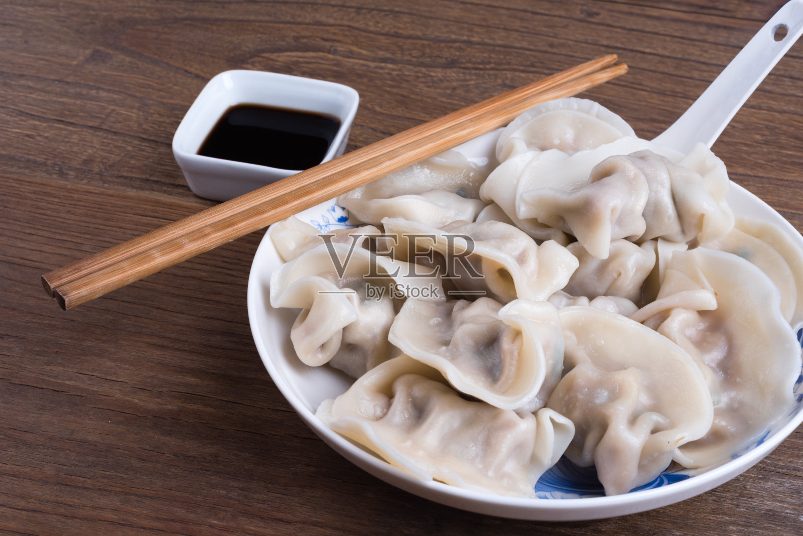 放在木桌上的装有蒸好的中国饺子的盘子照片摄影图片