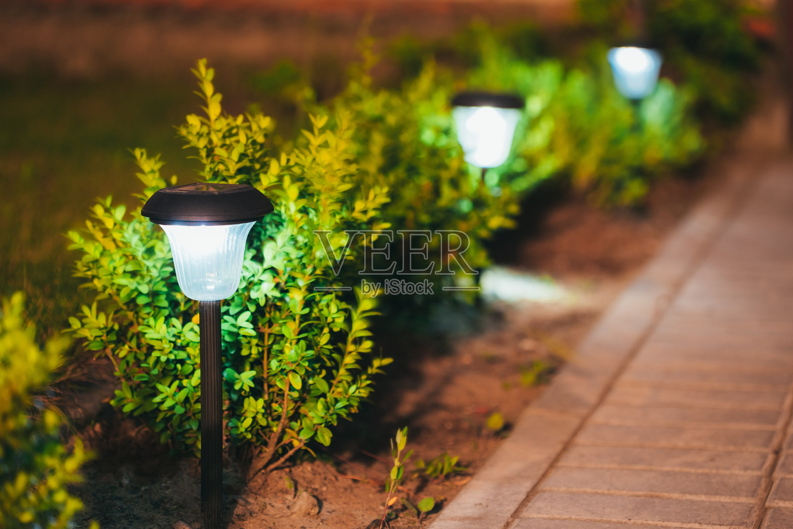 小型太阳能花园灯，花坛灯笼。花园的设计。照片摄影图片