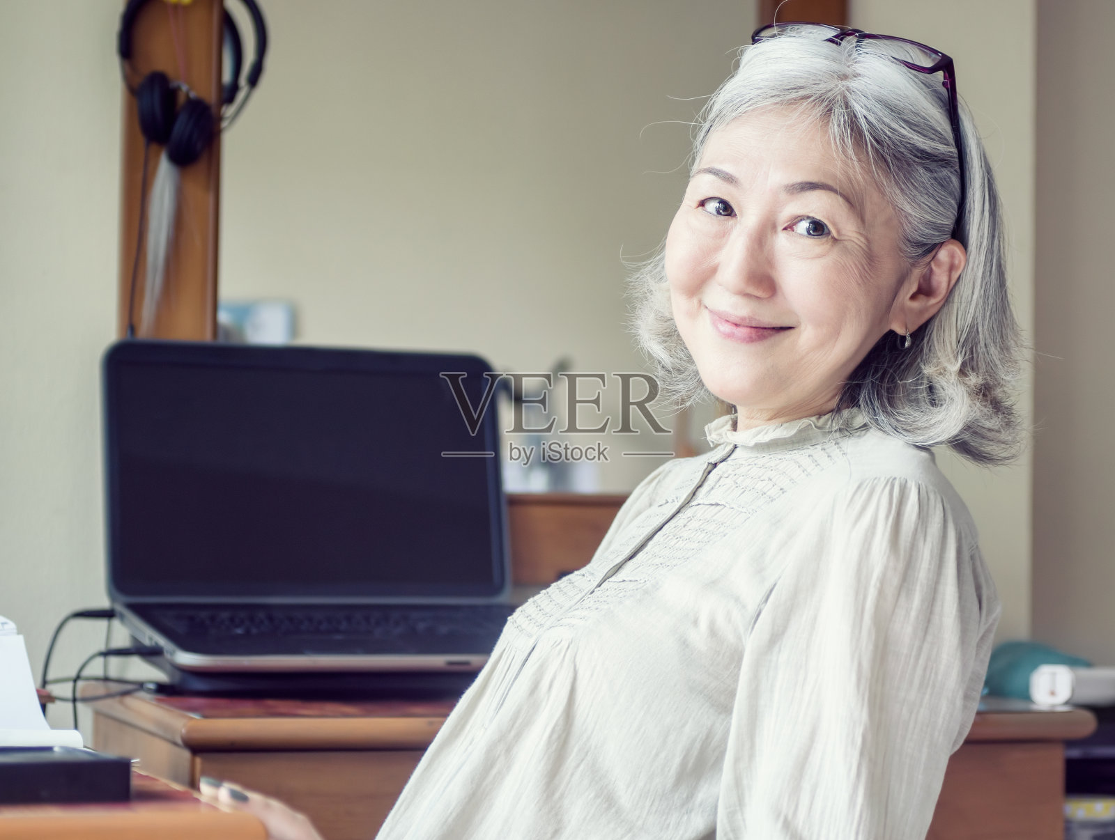 一位亚洲年长女性向后靠在椅子上，面带微笑照片摄影图片