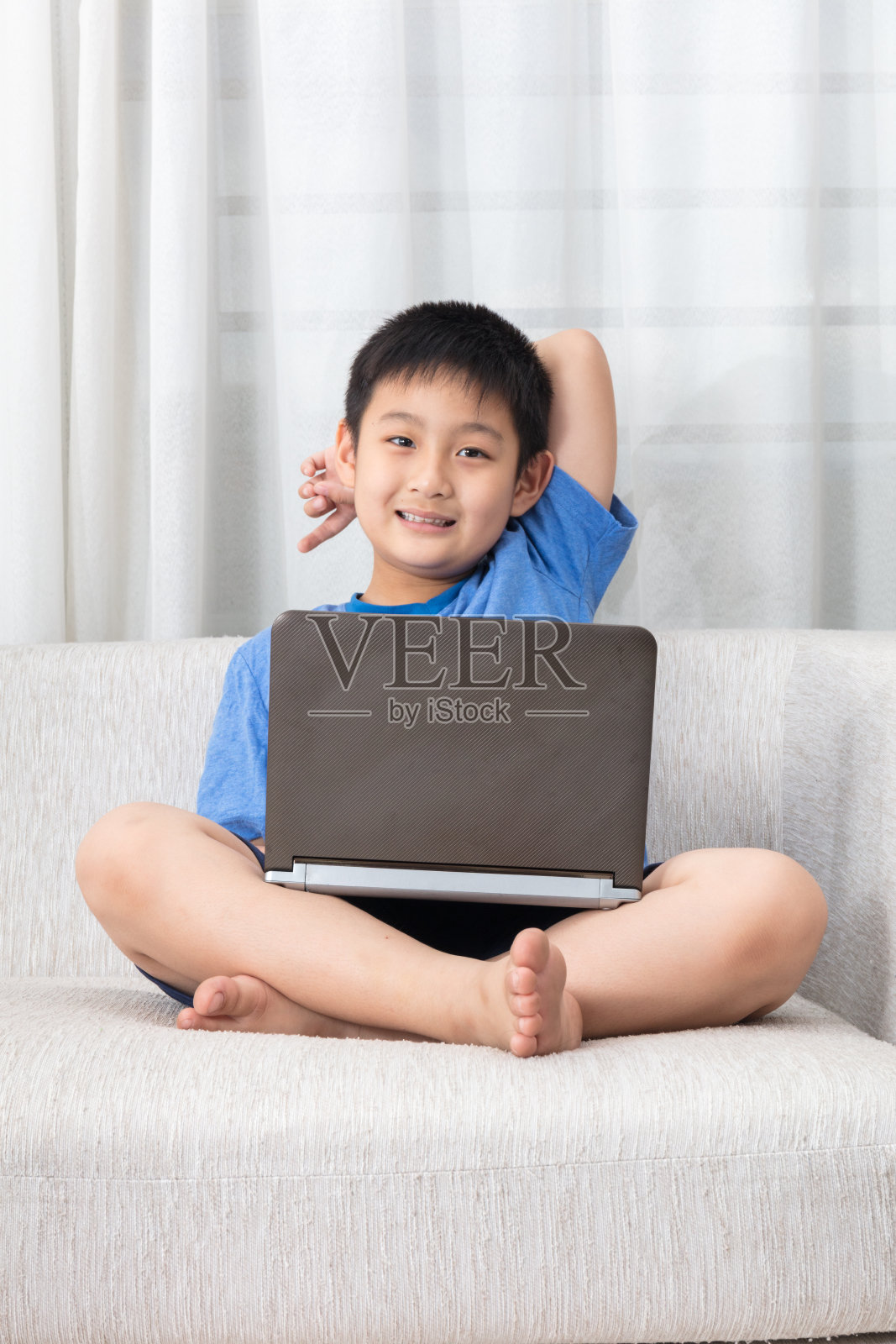 快乐的亚洲华人小男孩在沙发上使用笔记本电脑照片摄影图片