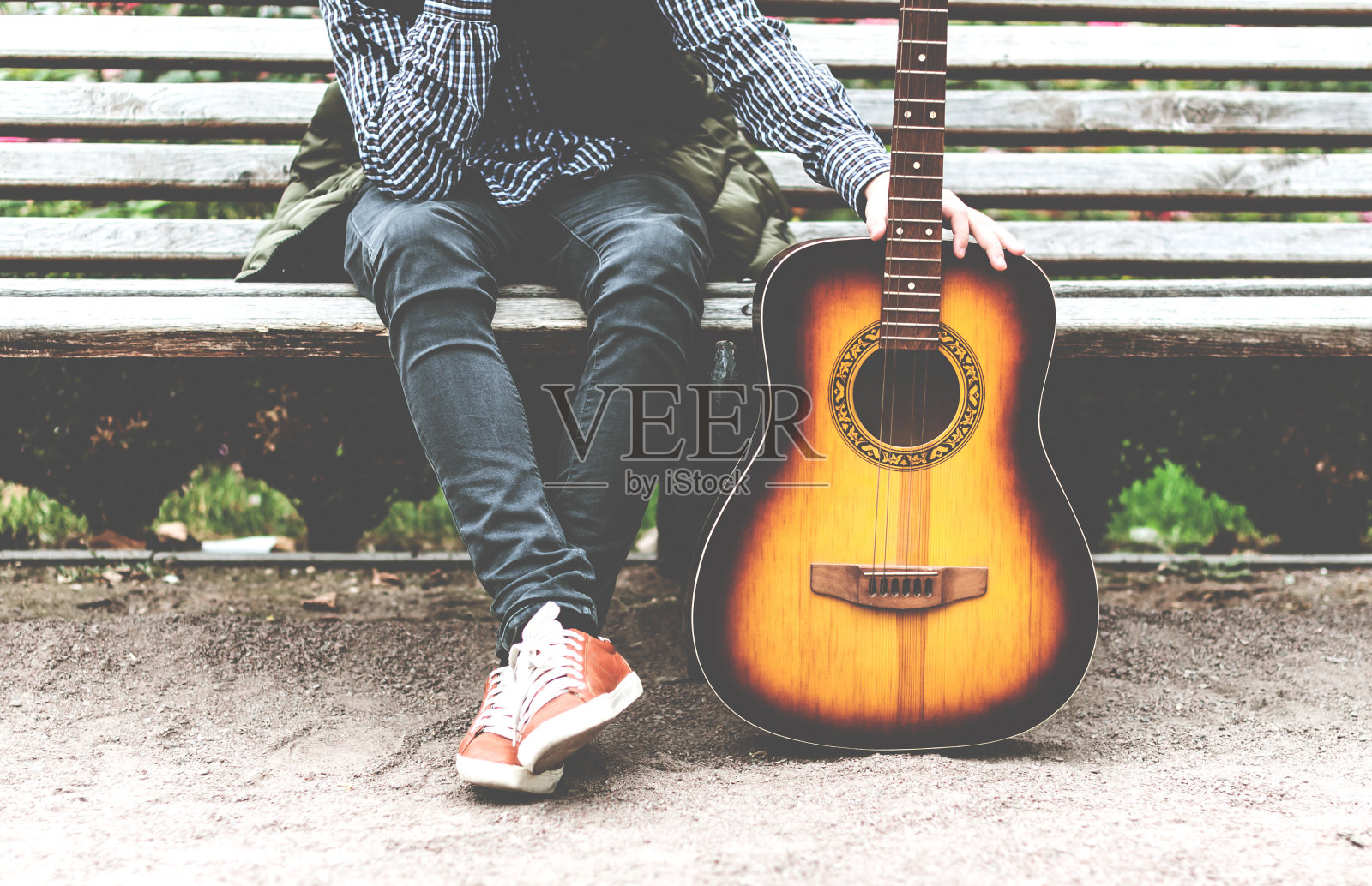 一个年轻人拿着吉他坐在长凳上照片摄影图片