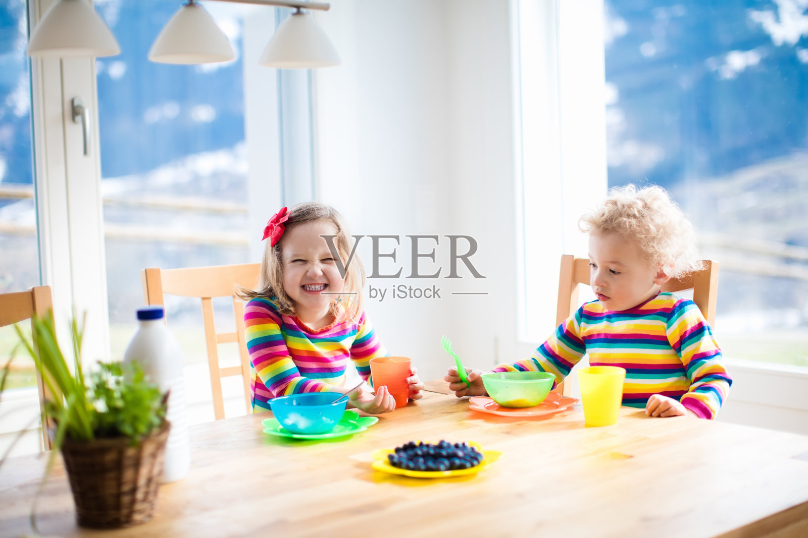 孩子和兄弟姐妹吃早餐。孩子们的水果和牛奶。照片摄影图片