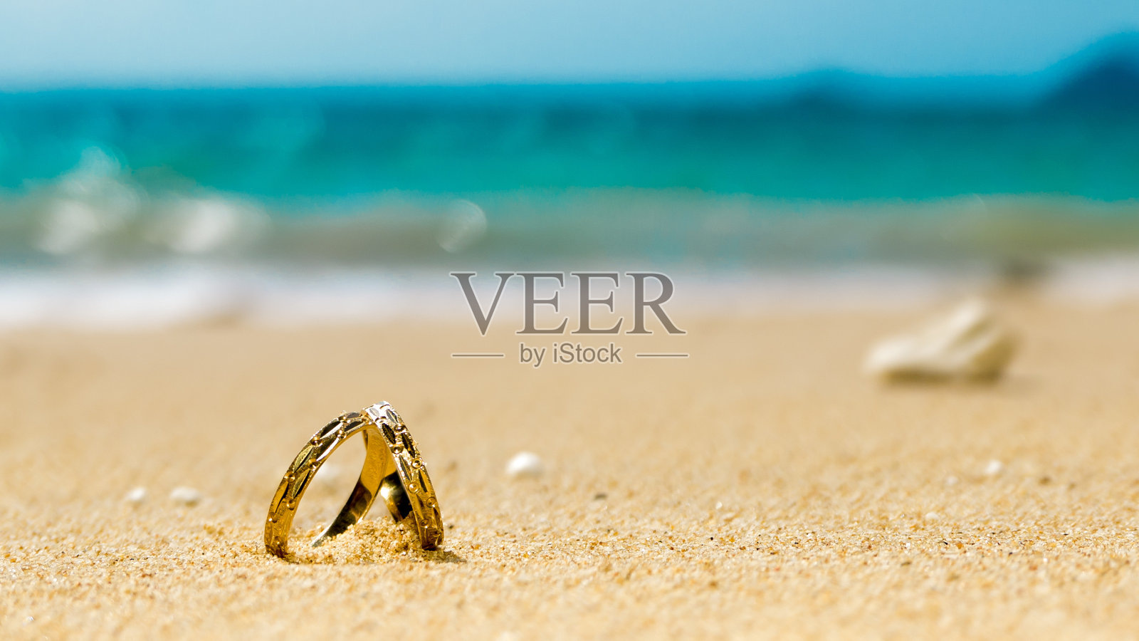 在热带岛屿度蜜月，在海滩上戴两个结婚戒指照片摄影图片