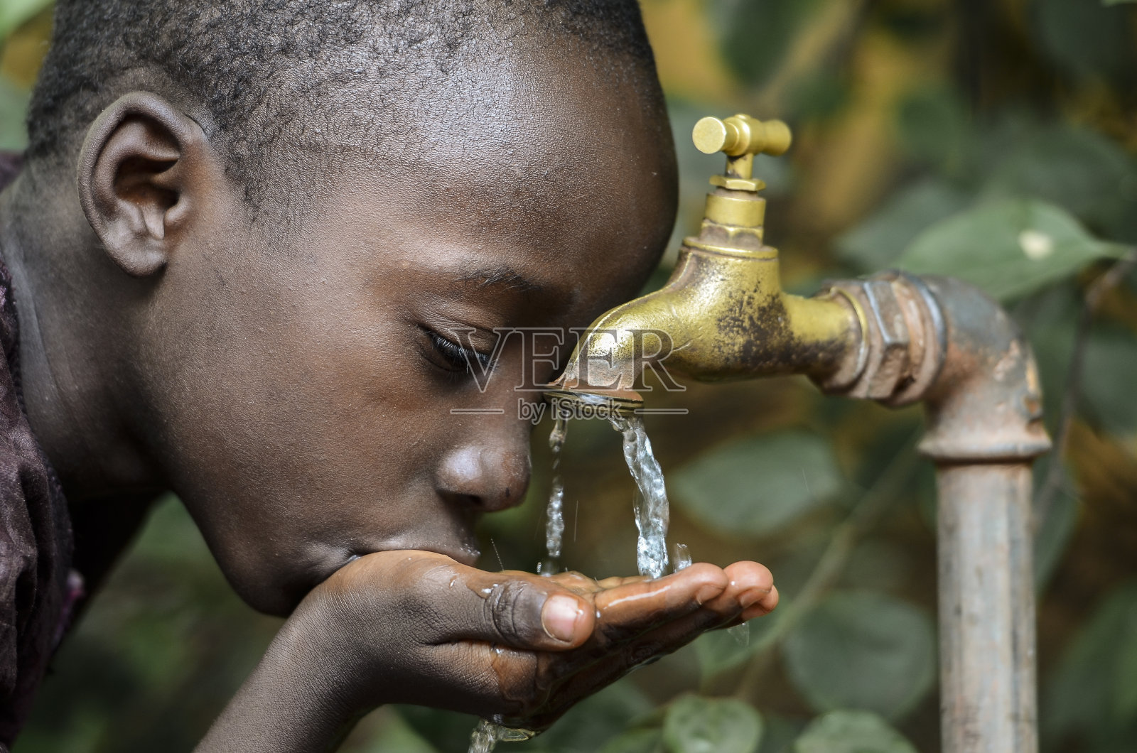 非洲小男孩从水龙头里喝健康干净的水照片摄影图片