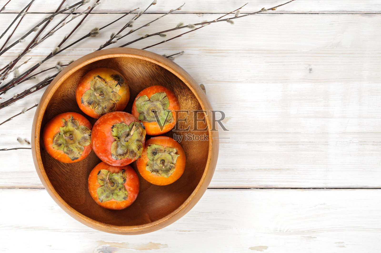 熟柿子装在一个木碗里，上面插着柳条照片摄影图片