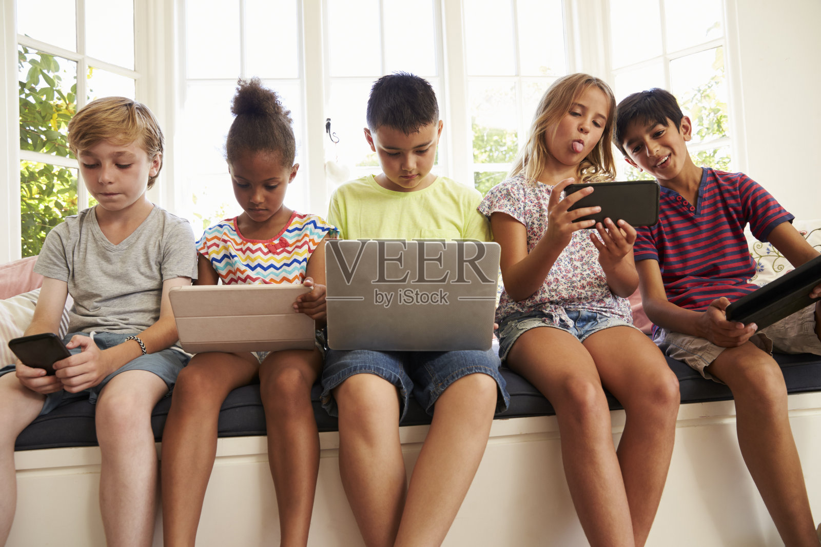 一群孩子坐在靠窗的座位上使用科技照片摄影图片