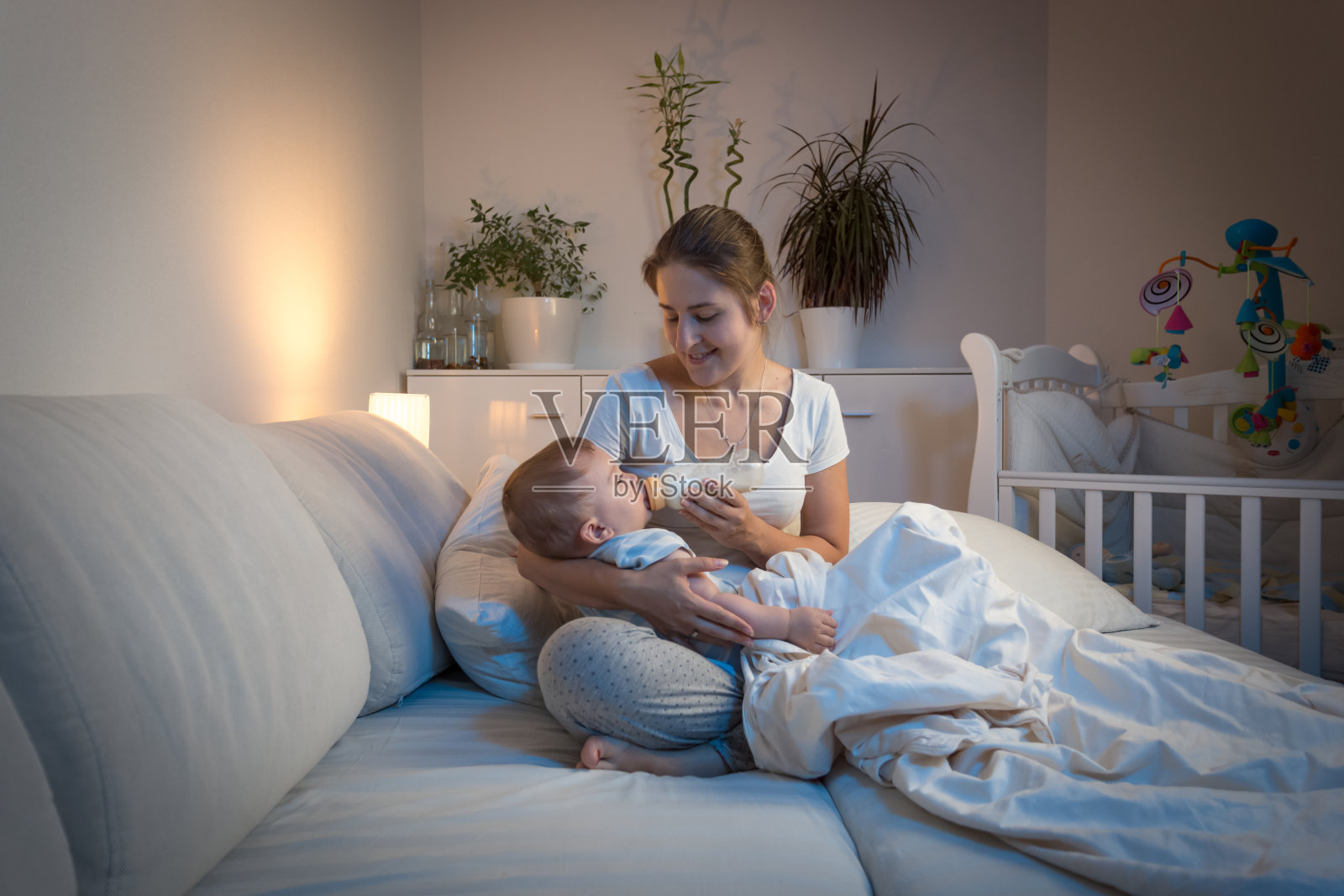 年轻的母亲坐在沙发上给刚出生的婴儿喂奶照片摄影图片_ID:419050246-Veer图库