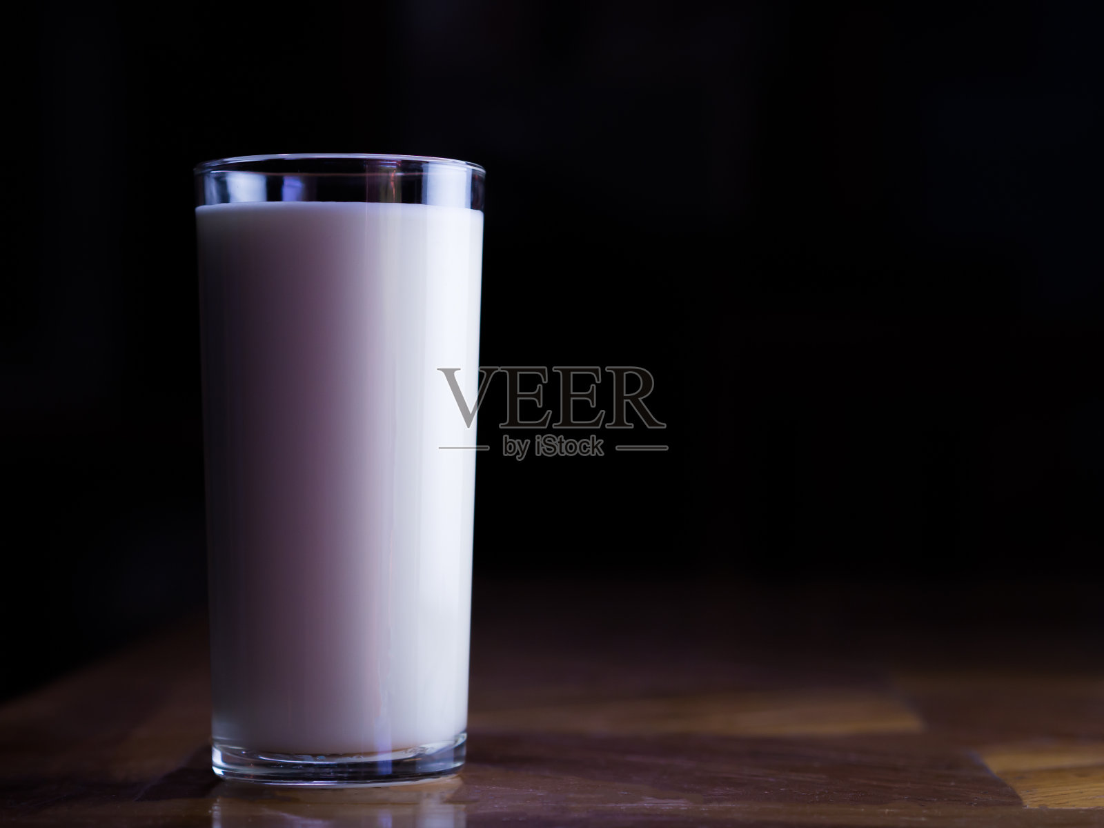 木桌上放着一杯牛奶。喝酒的好处。照片摄影图片