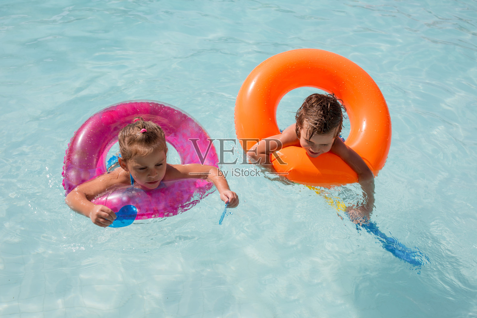 两个孩子在游泳池里享受。照片摄影图片