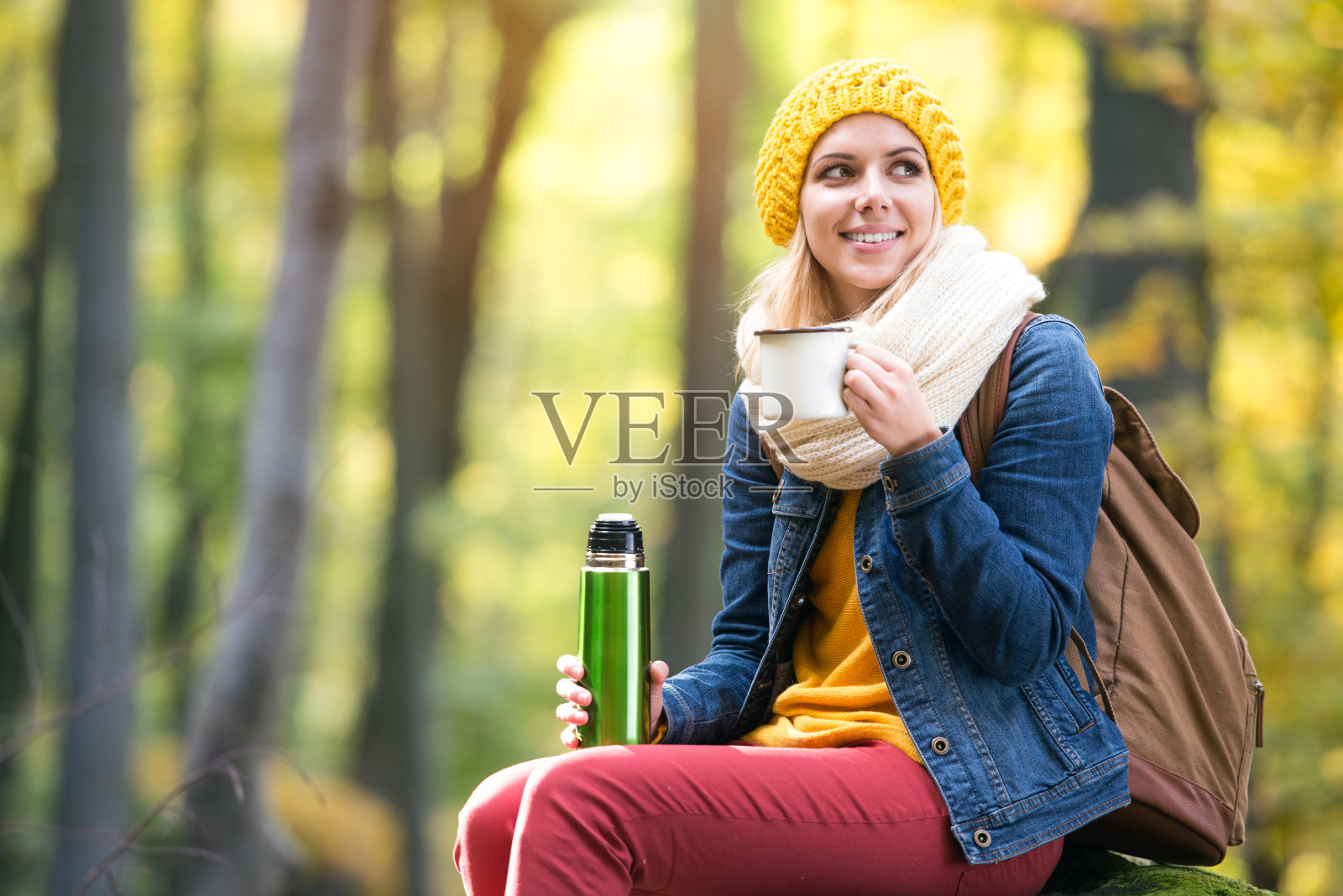 美丽的女人在秋天的森林，热水瓶和杯子照片摄影图片
