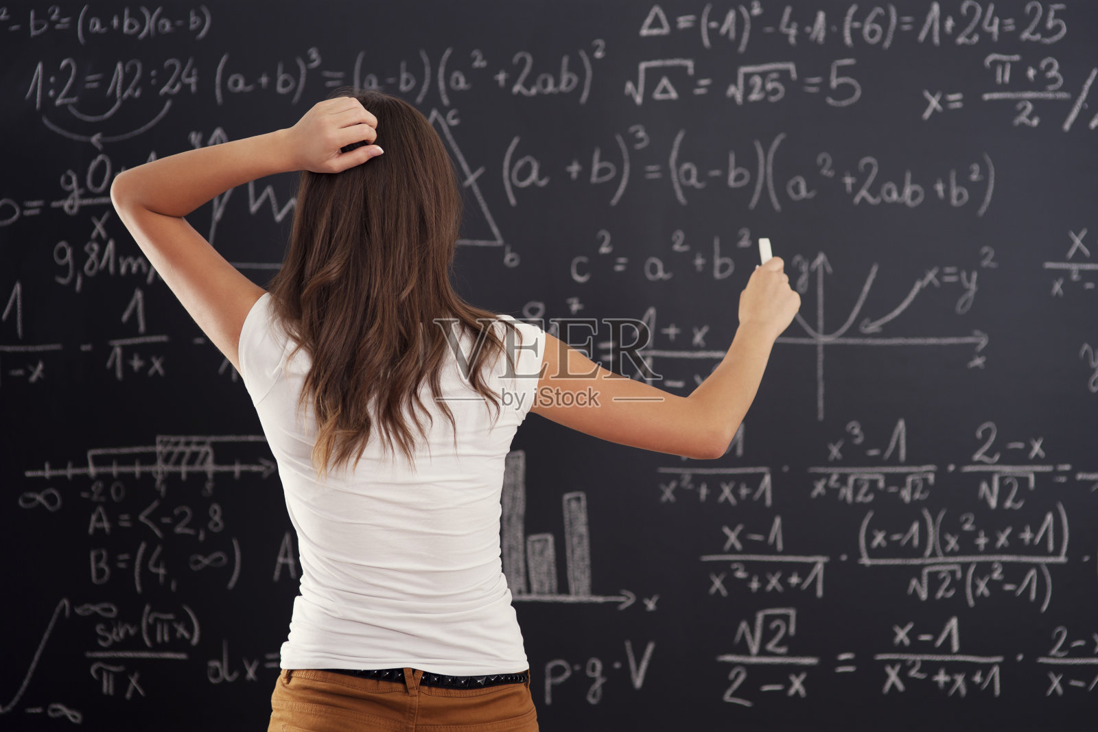 一位年轻女子正在看黑板上的数学题照片摄影图片