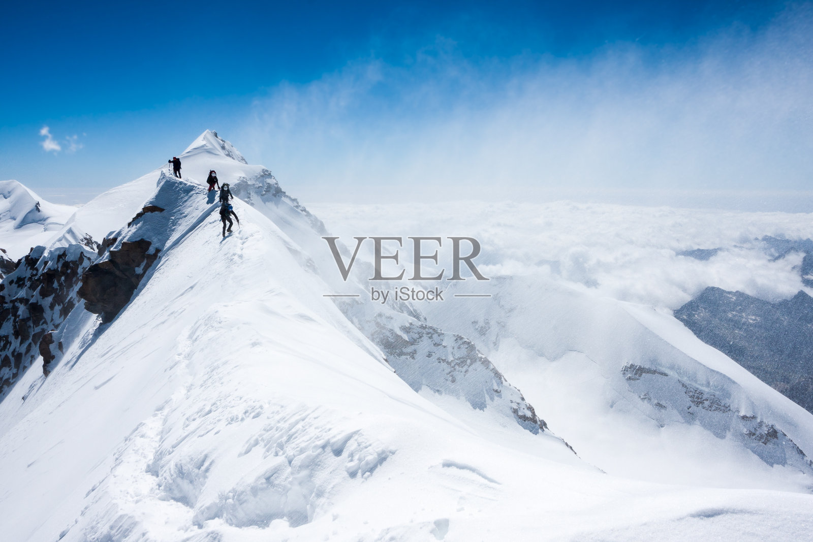登山者在暴风雪中在狭窄的山脊上保持平衡照片摄影图片