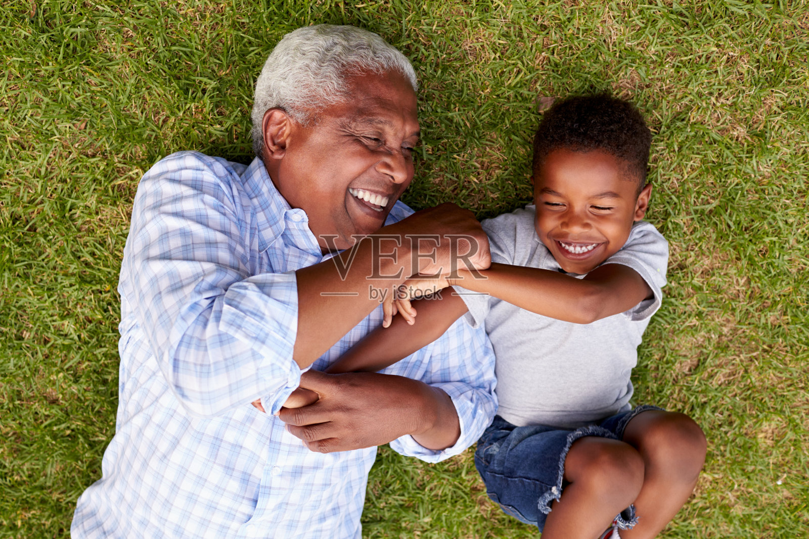 爷爷和孙子躺在草地上玩，鸟瞰照片摄影图片