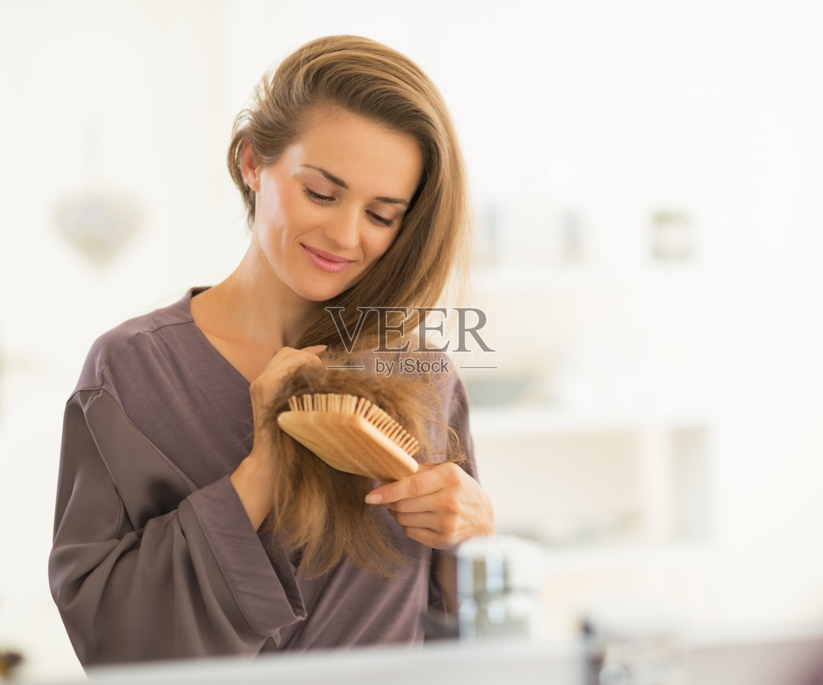 在浴室梳头的快乐年轻女人照片摄影图片