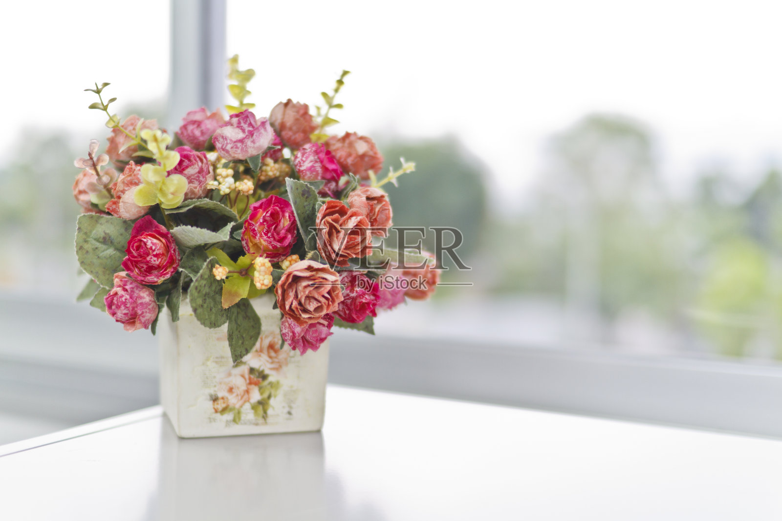 白色桌子上放着一只装满粉红色花朵的花瓶照片摄影图片