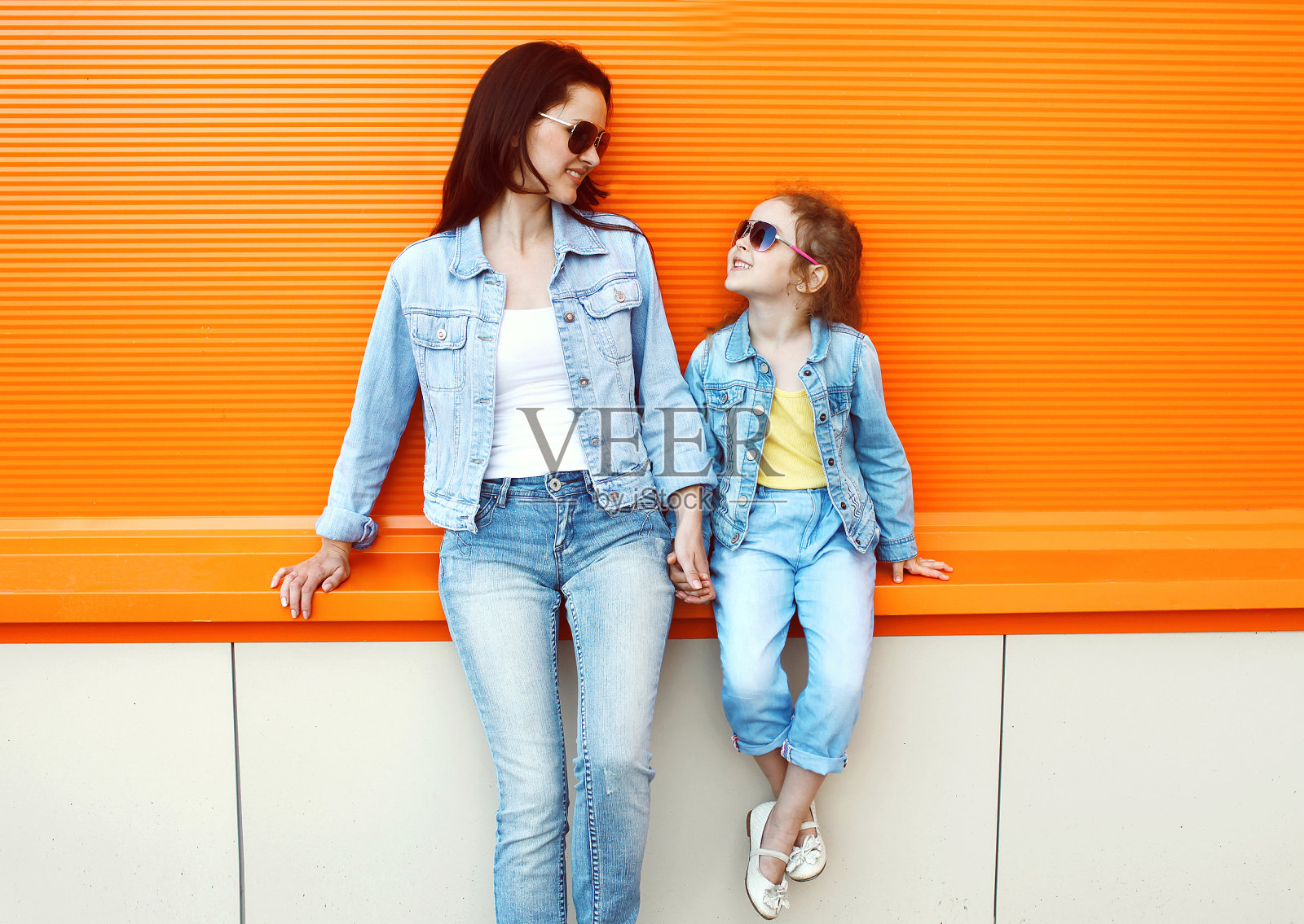 快乐的妈妈和孩子穿着牛仔裤的衣服在城市里照片摄影图片