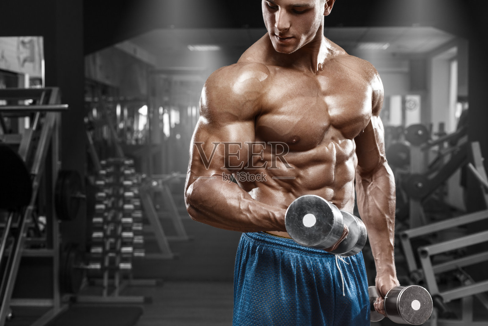 肌肉男在健身房锻炼。强壮的男性躯干腹肌照片摄影图片