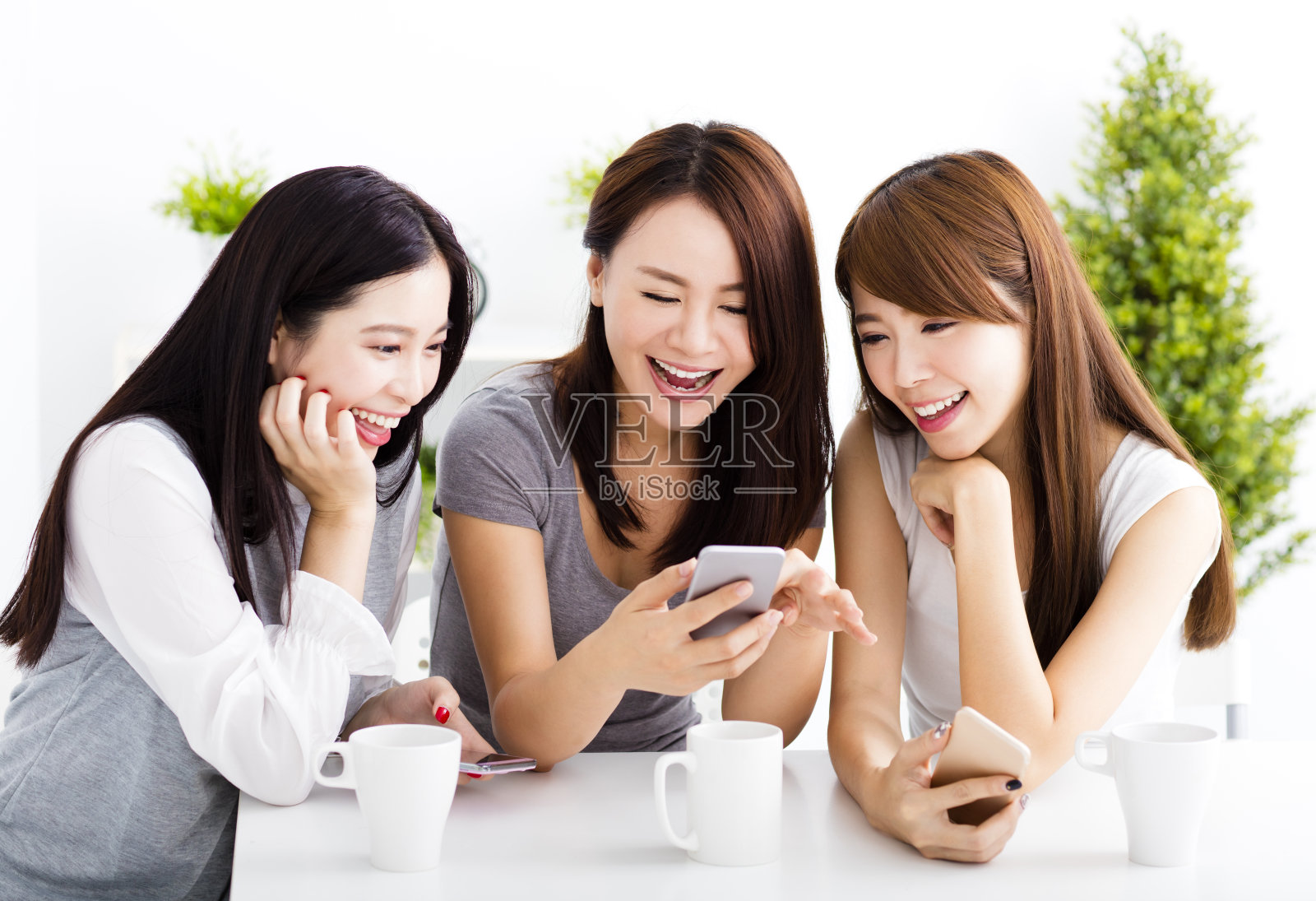 快乐的年轻女人在客厅看智能手机照片摄影图片