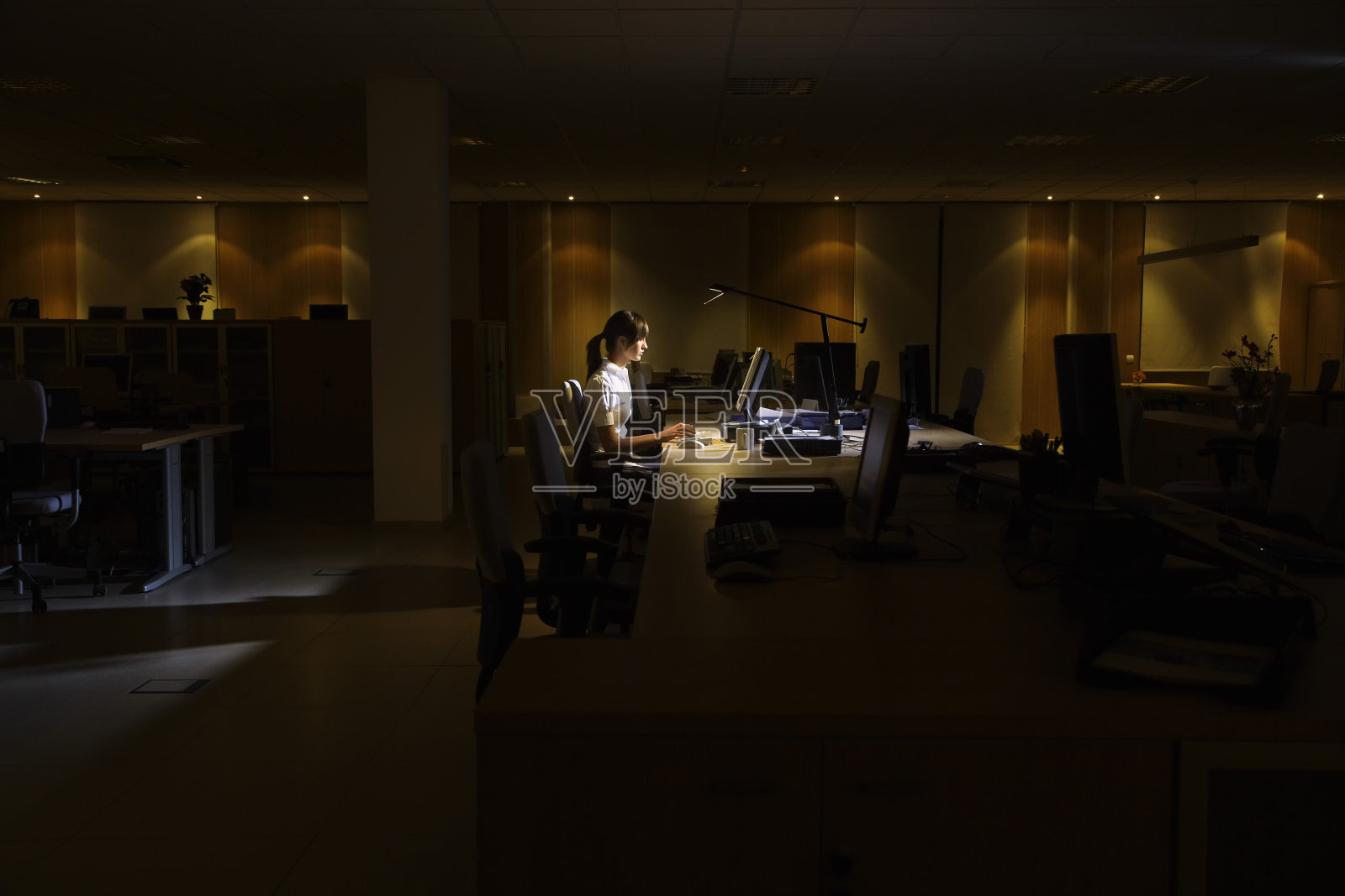 在黑暗的办公室里使用电脑的女人照片摄影图片