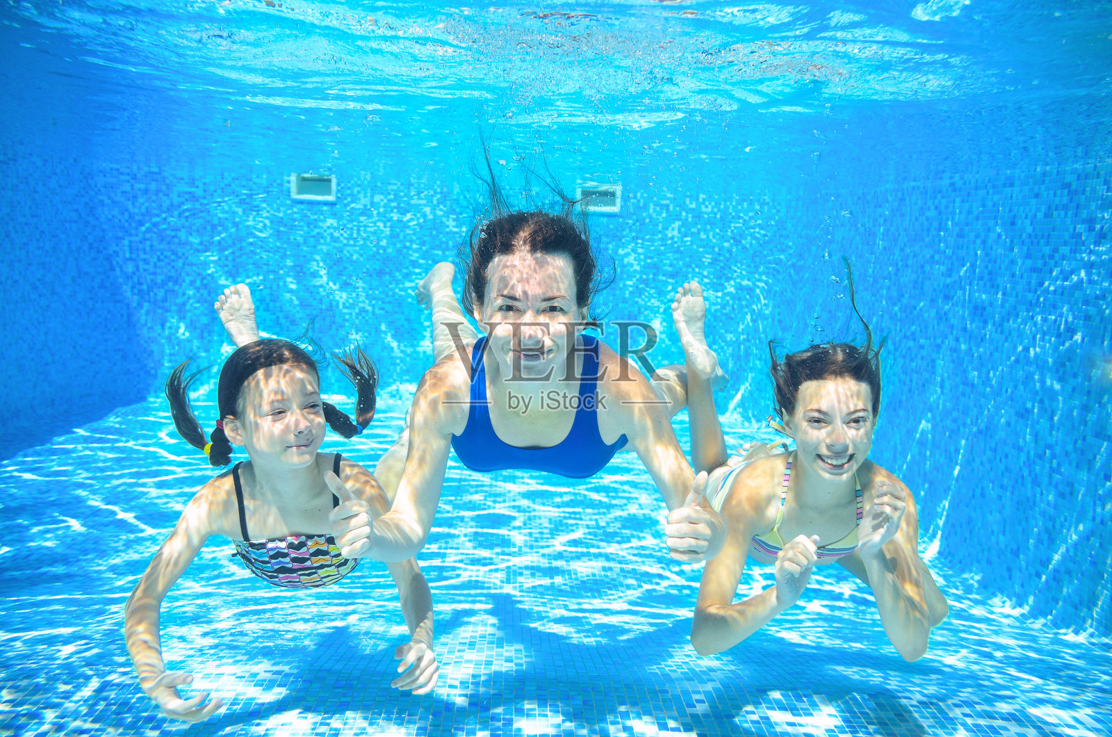 一家人在水下游泳池游泳，母亲和孩子在水下照片摄影图片