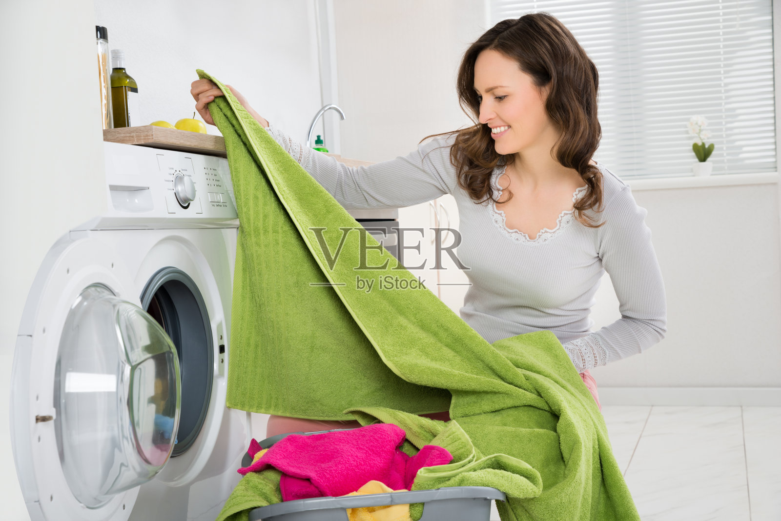 女人在洗衣机里洗衣服照片摄影图片