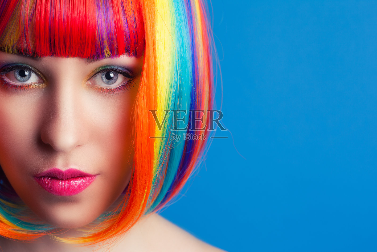 美丽的女人戴着彩色的假发在蓝色的背景照片摄影图片