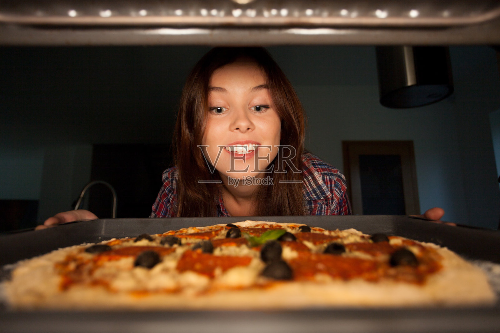 快乐女孩把披萨放进烤箱照片摄影图片