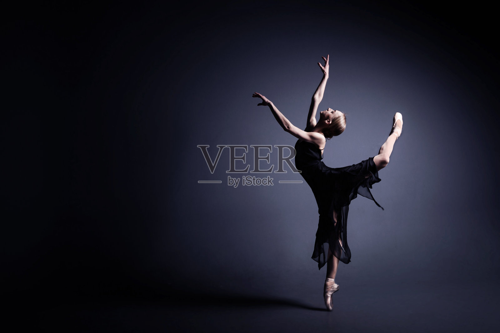 年轻的芭蕾舞女演员穿着黑色的衣服在黑暗中跳舞照片摄影图片