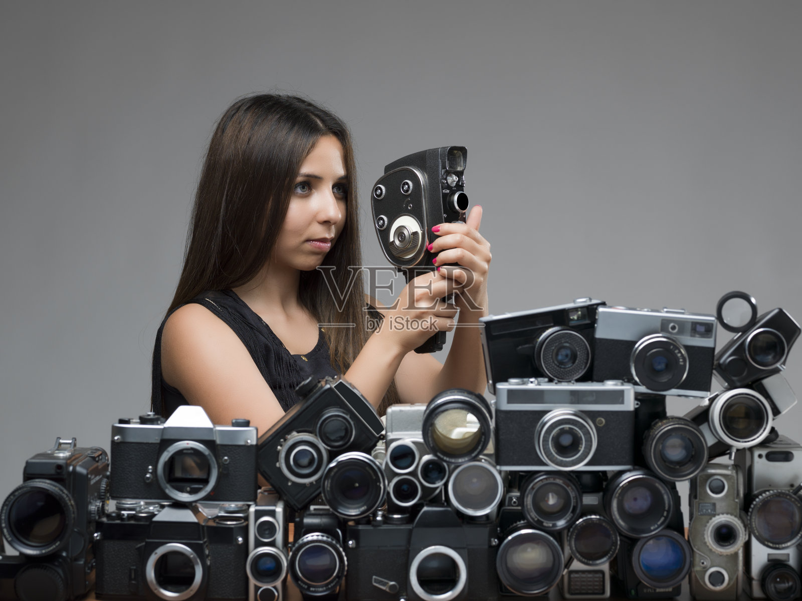 一个年轻女子拿着相机躲在一大群物体后面照片摄影图片
