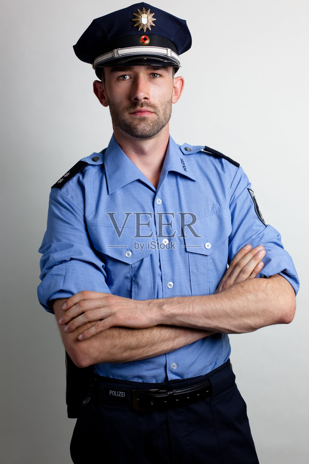 一名身穿蓝色制服、双臂交叉的警察的肖像照片摄影图片