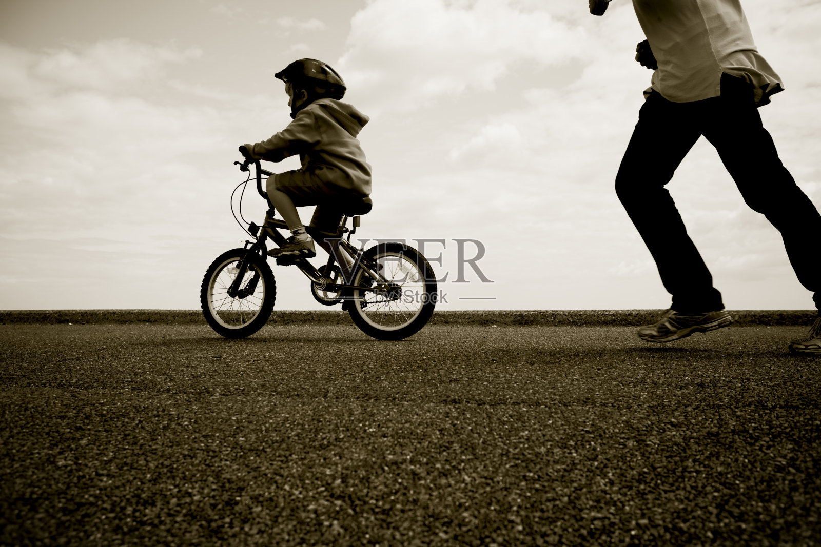 父亲追着一个学骑车的年轻人照片摄影图片