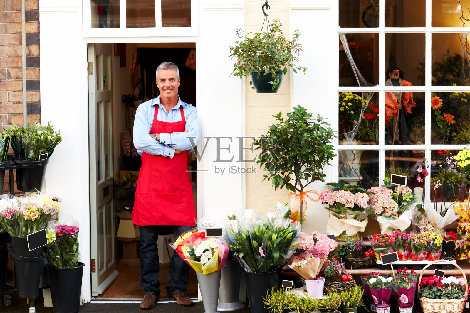 成熟的男花匠微笑着在花店工作照片摄影图片