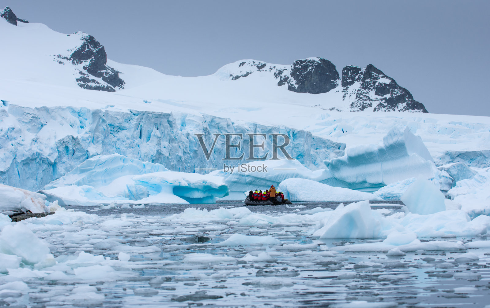 一艘载着游客的船漂浮在南极洲的冰山之间照片摄影图片