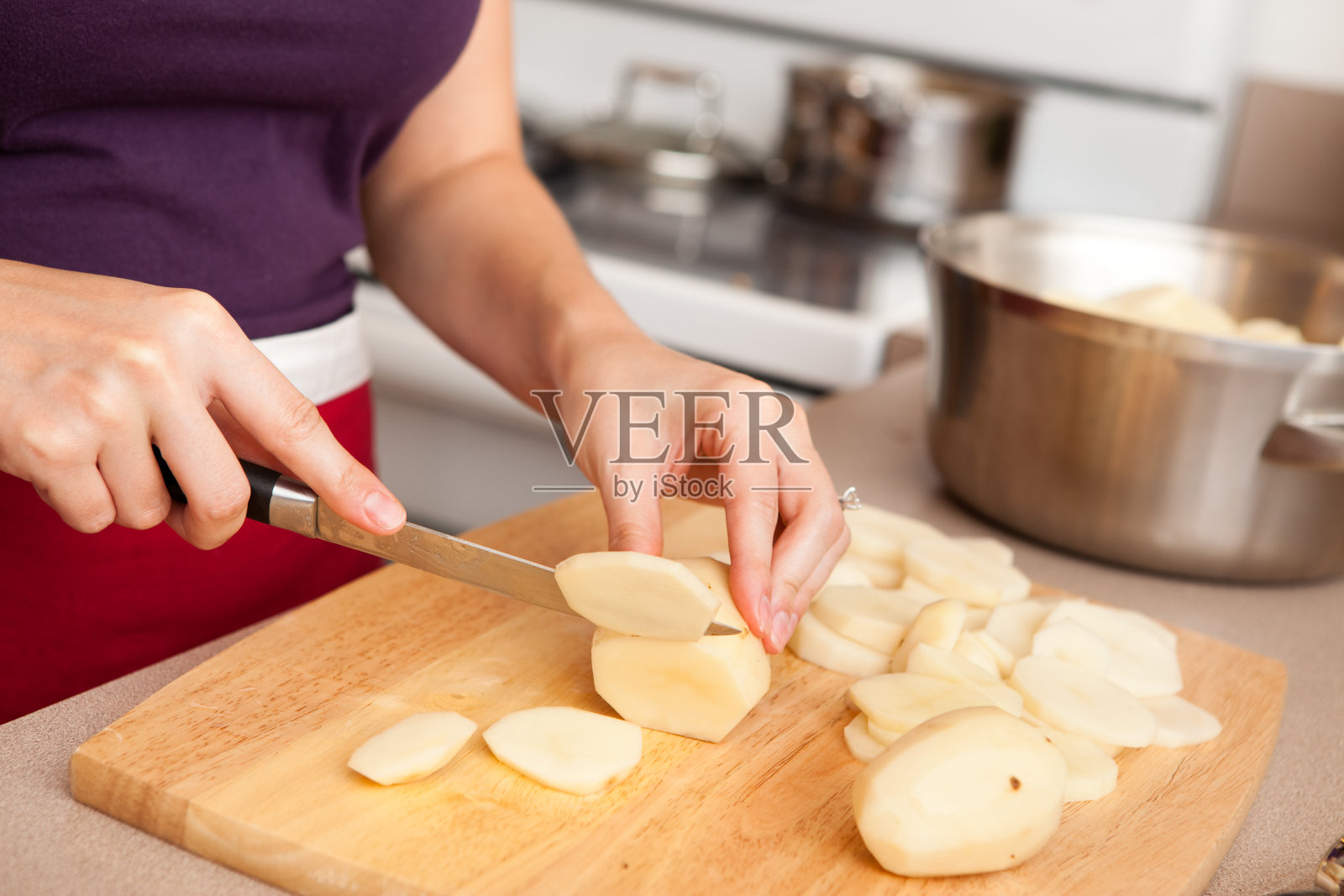 年轻女子在家厨房切红褐色土豆照片摄影图片