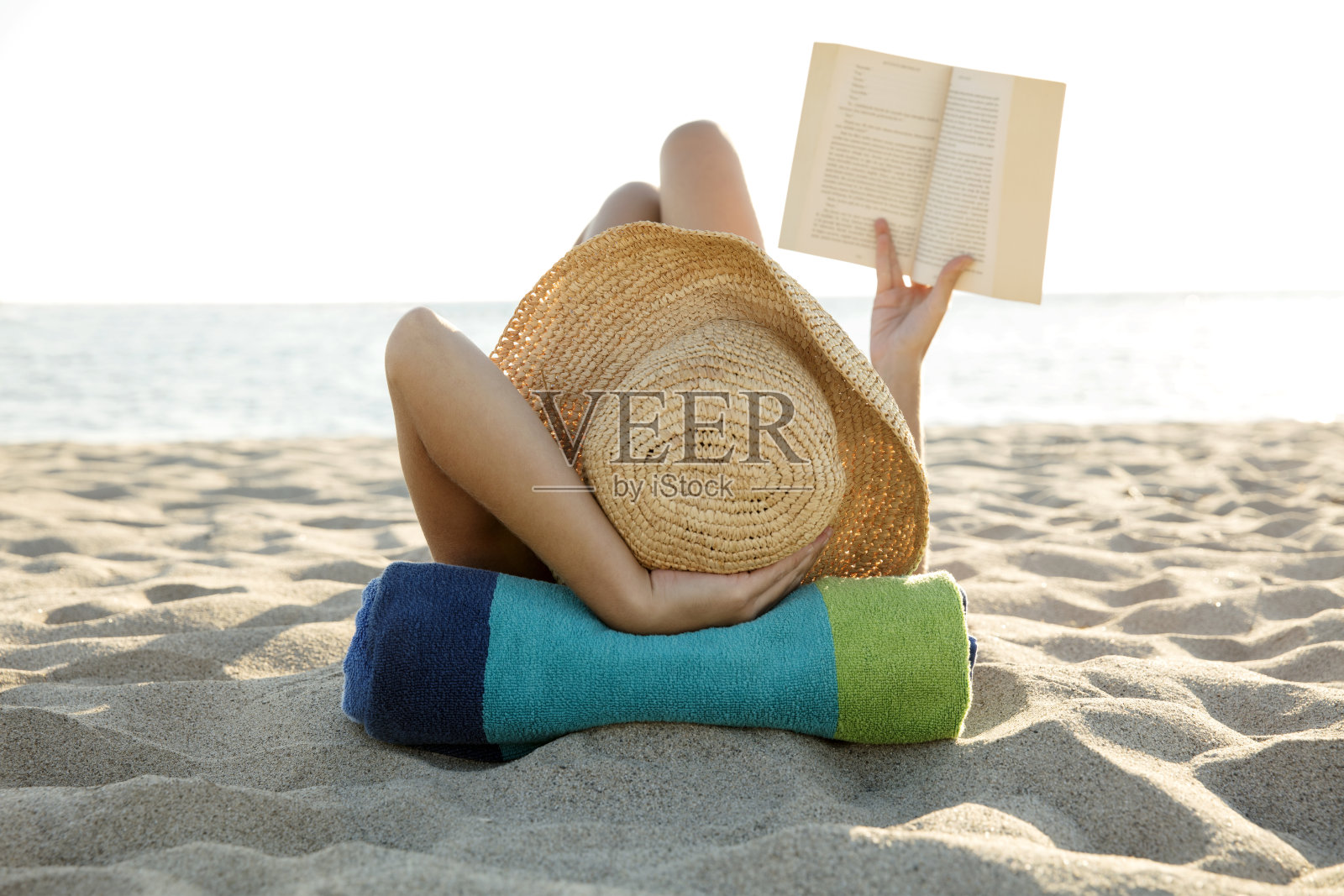 一个女人躺在沙滩上看书照片摄影图片