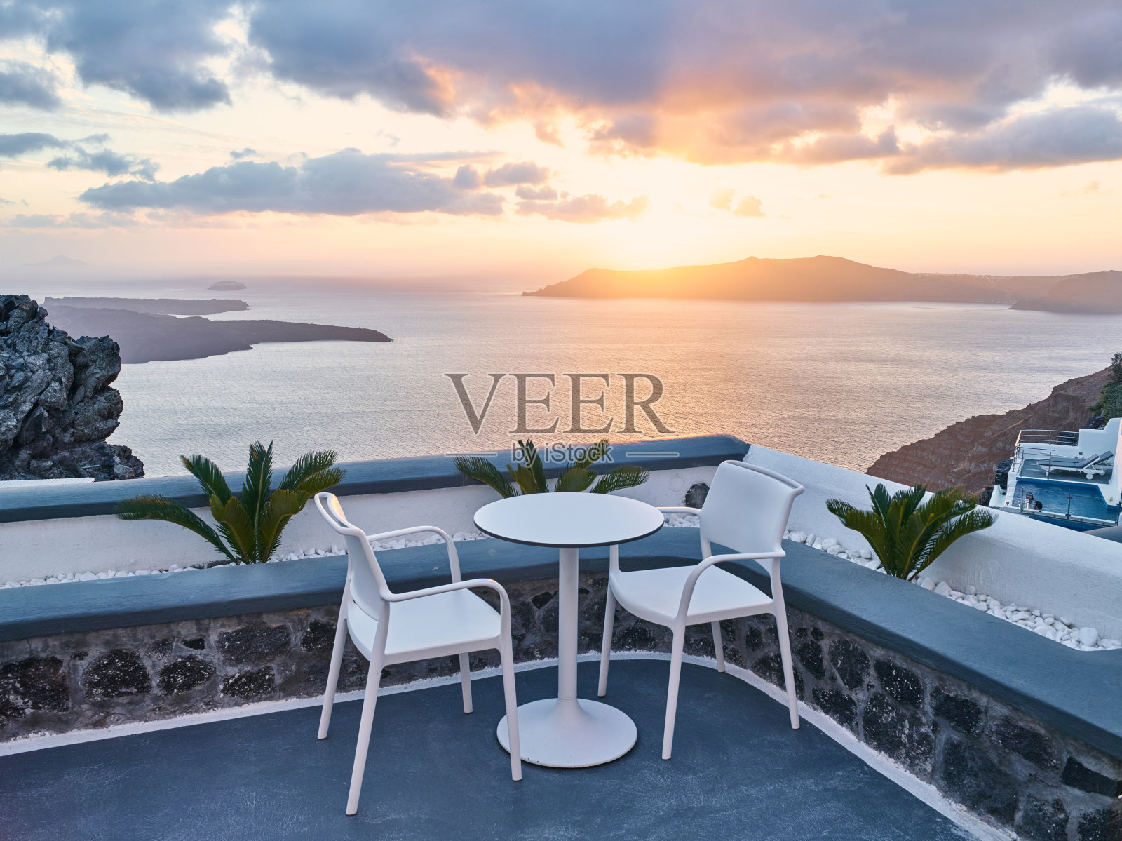 两张椅子和一张小桌子，在美丽的露台上可以看到希腊圣托里尼的美丽海景照片摄影图片