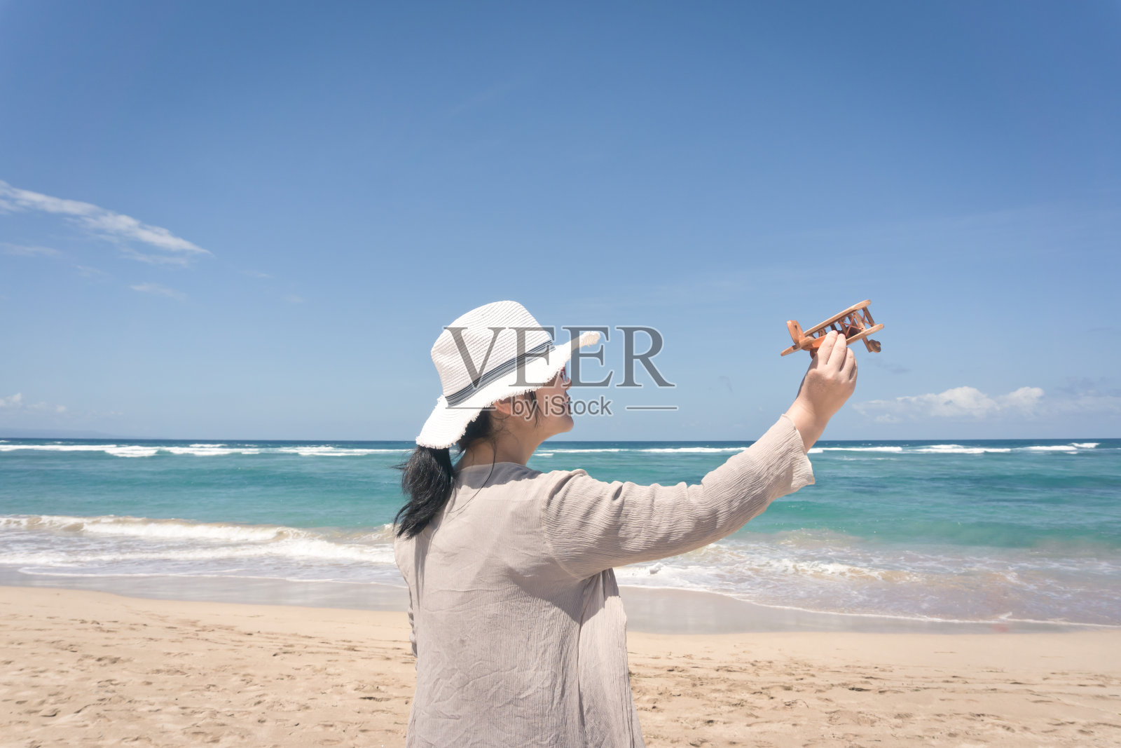 年轻女子在海滩上玩木飞机照片摄影图片
