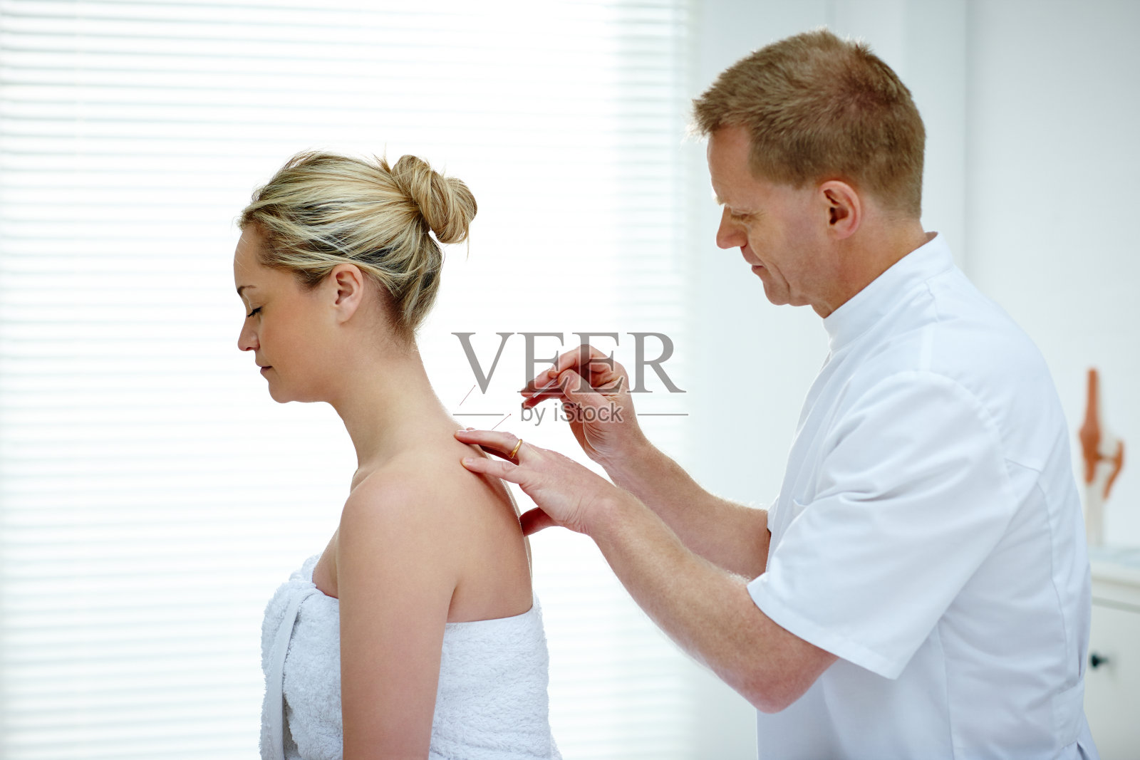 理疗师在女性病人的背部做针灸照片摄影图片