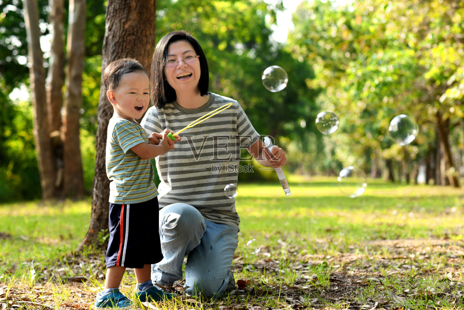 亚洲小孩和妈妈玩泡泡棒照片摄影图片