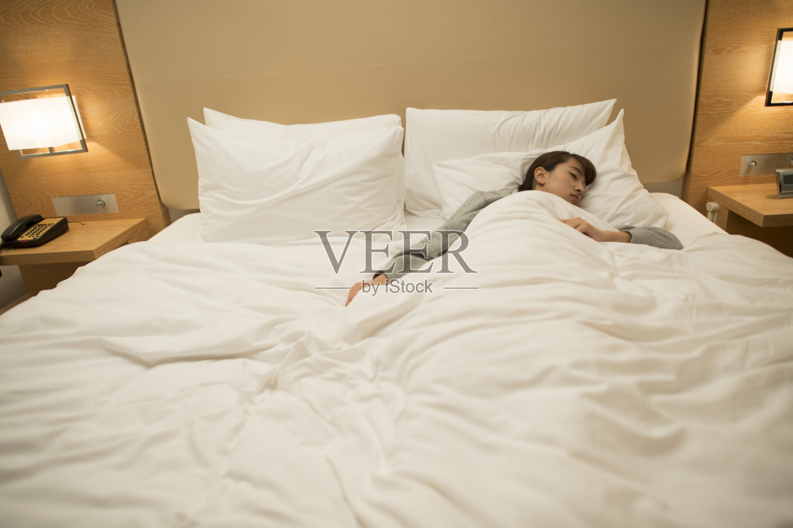 一个女人睡在白色的床上照片摄影图片