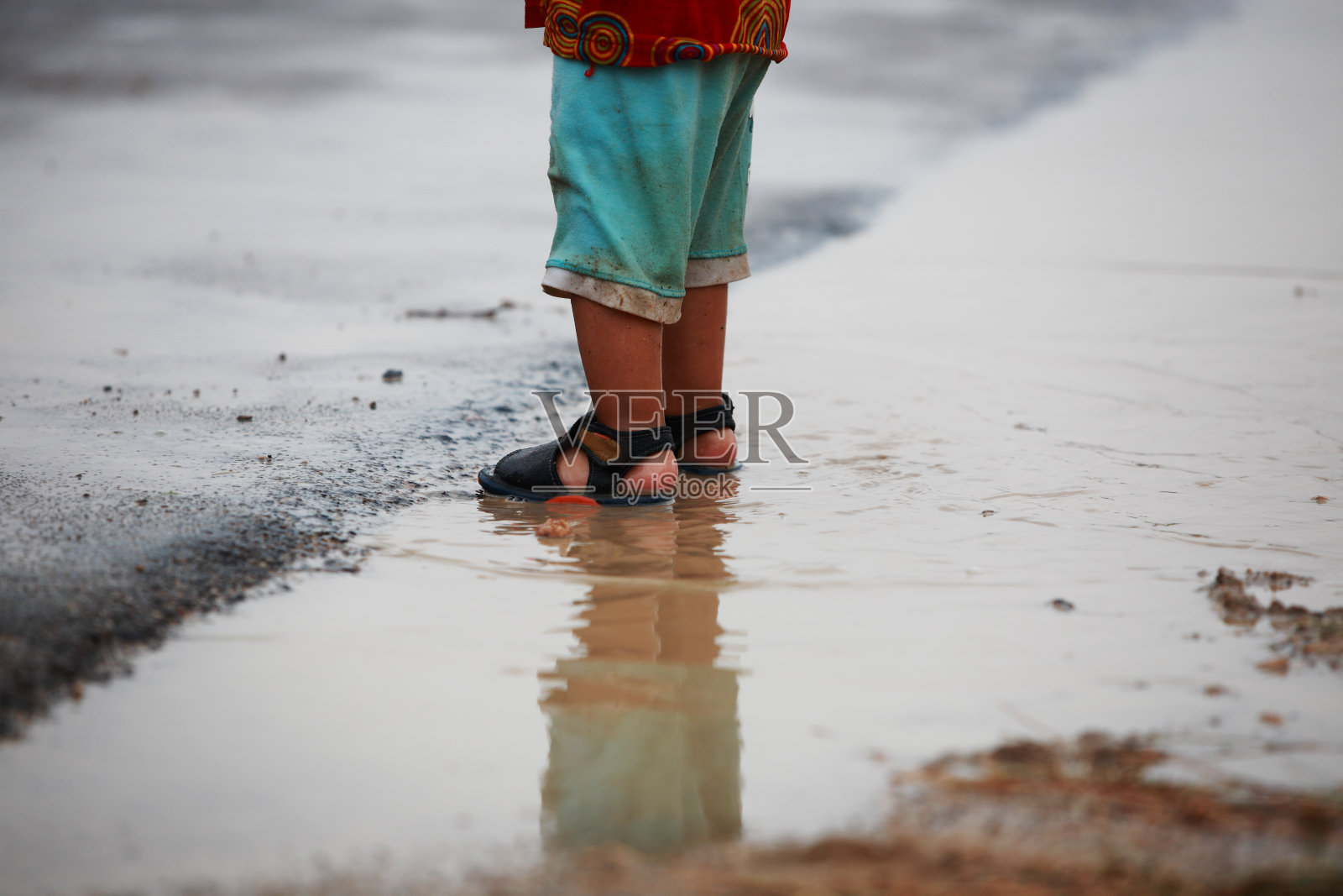 小男孩玩自由雨水水坑溅水照片摄影图片
