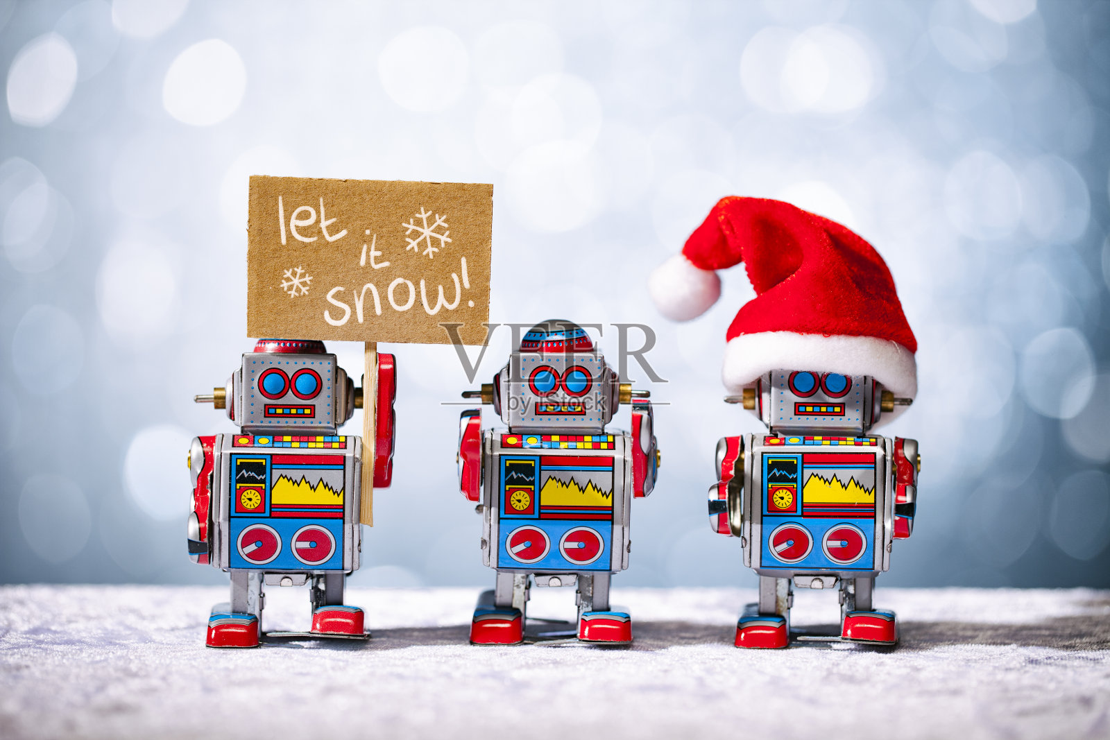 三个复古机器人为圣诞节摆姿势。让它下雪了。圣诞老人。照片摄影图片