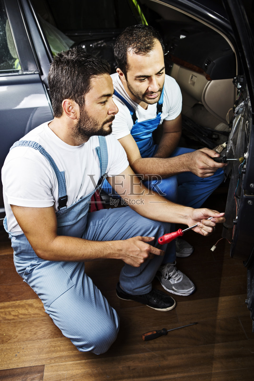 年轻的机械师在汽车修理厂修理汽车照片摄影图片