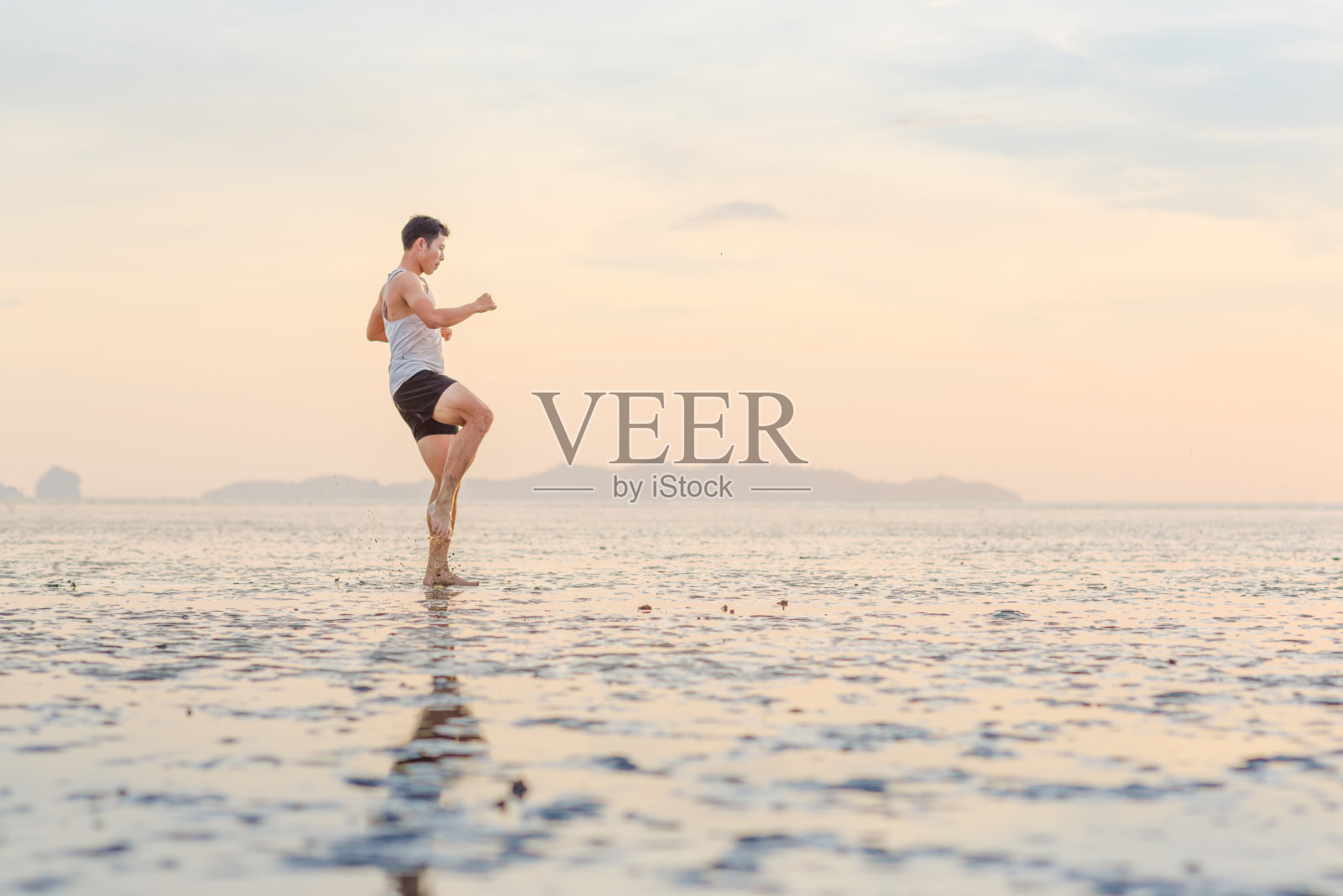 年轻的亚洲男子训练空手道和踢拳击在海滩照片摄影图片
