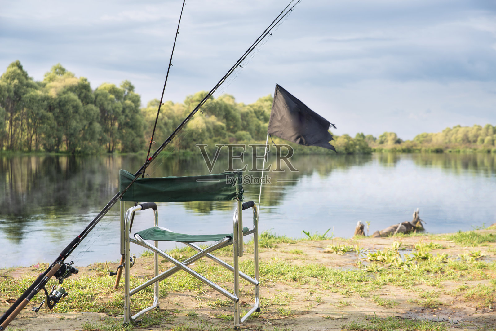 在大河边的一个椅子旁边钓钓竿。照片摄影图片
